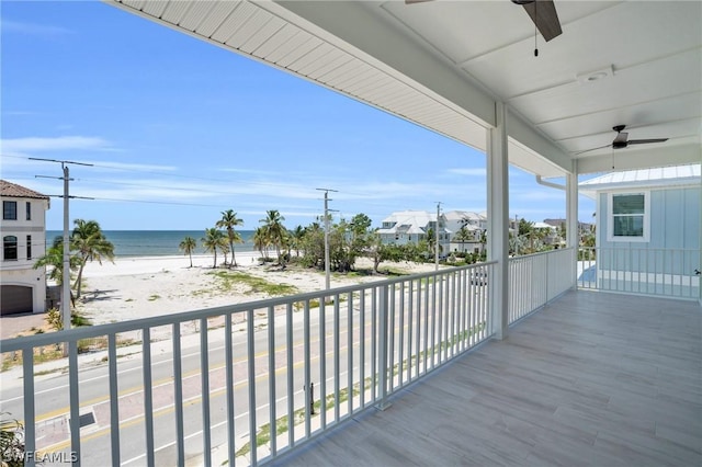 balcony featuring ceiling fan, a water view, and a view of the beach