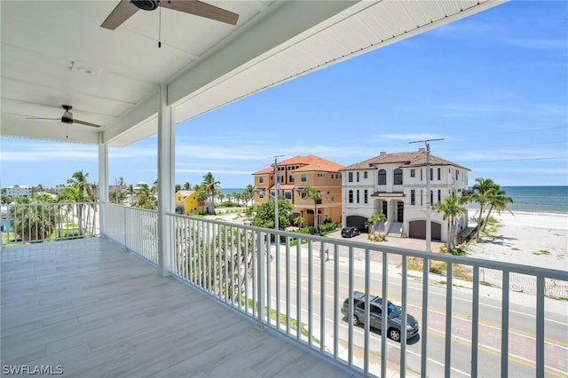 balcony featuring ceiling fan, a water view, and a view of the beach