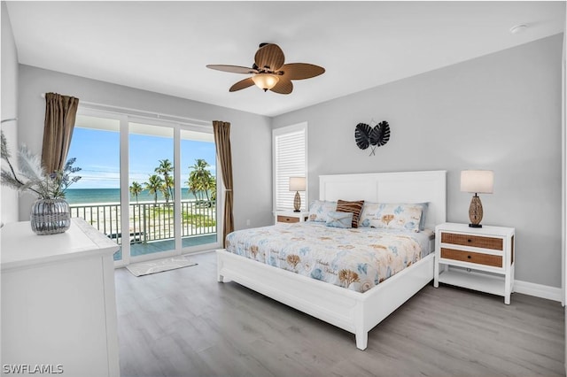 bedroom featuring access to outside, a water view, ceiling fan, and wood-type flooring