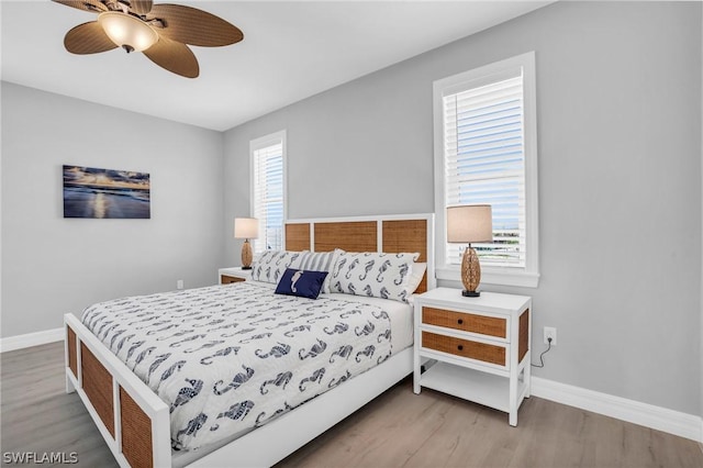 bedroom featuring ceiling fan, multiple windows, and light hardwood / wood-style flooring