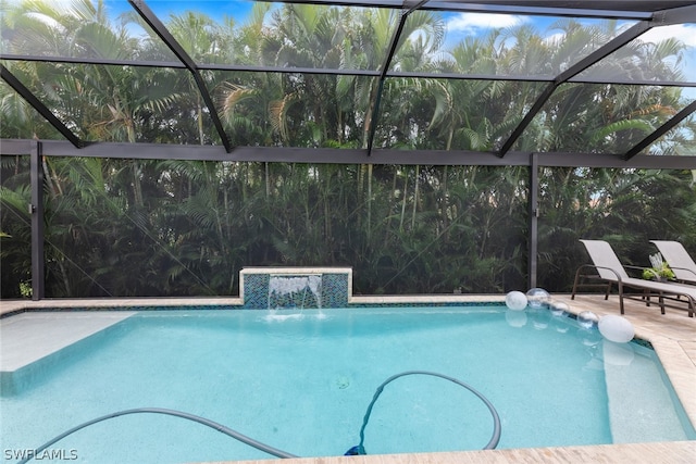 view of pool with pool water feature and glass enclosure