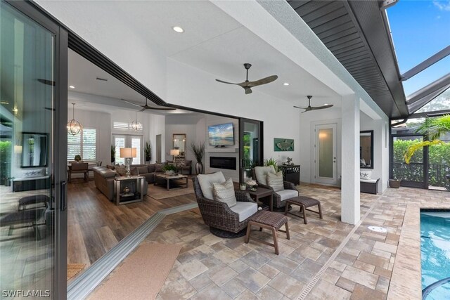 view of patio / terrace with an outdoor pool, glass enclosure, ceiling fan, and an outdoor living space