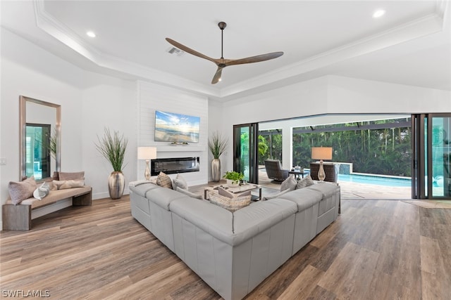 living room with hardwood / wood-style flooring, a raised ceiling, and ceiling fan