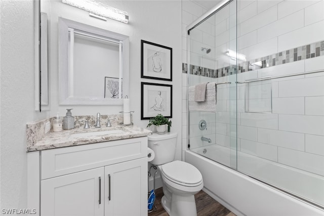 full bathroom featuring hardwood / wood-style flooring, toilet, vanity, and enclosed tub / shower combo