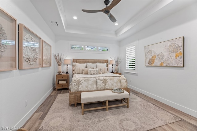 bedroom with ceiling fan, a raised ceiling, and hardwood / wood-style floors