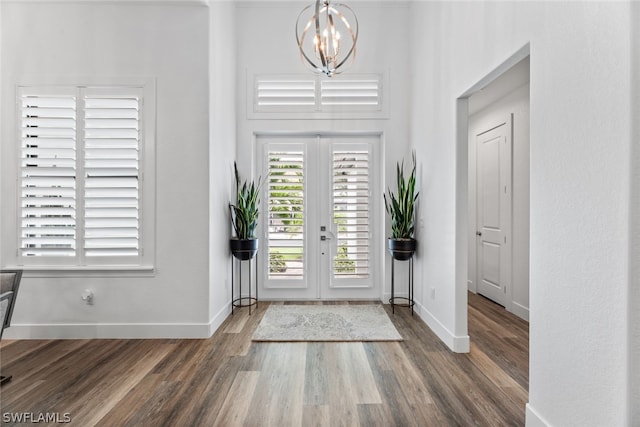 entrance foyer with a high ceiling, an inviting chandelier, french doors, and dark wood-type flooring