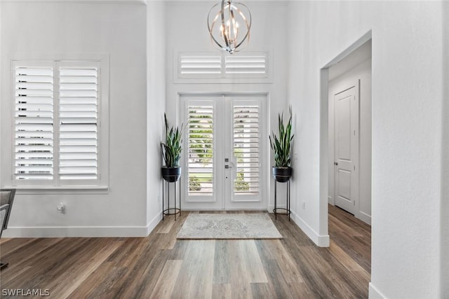 foyer entrance with baseboards, french doors, wood finished floors, and an inviting chandelier