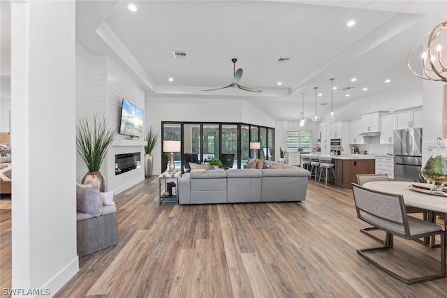 living room featuring ceiling fan, a raised ceiling, and light hardwood / wood-style floors