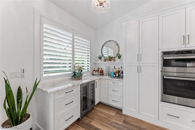 kitchen featuring beverage cooler, wood finished floors, stainless steel double oven, white cabinetry, and open shelves