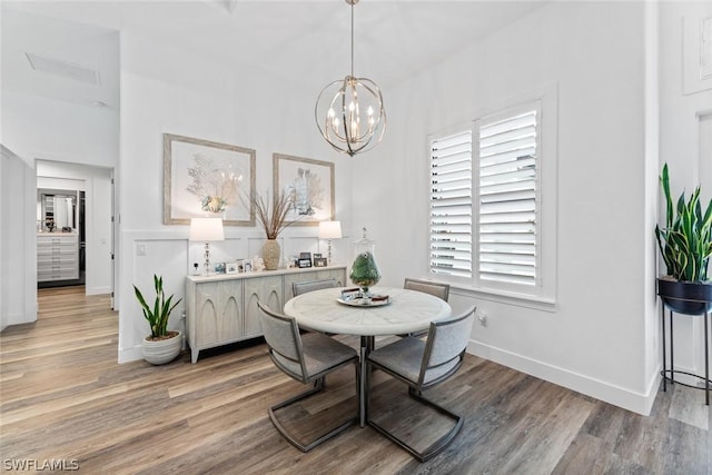 dining space featuring a chandelier, light wood-type flooring, and baseboards