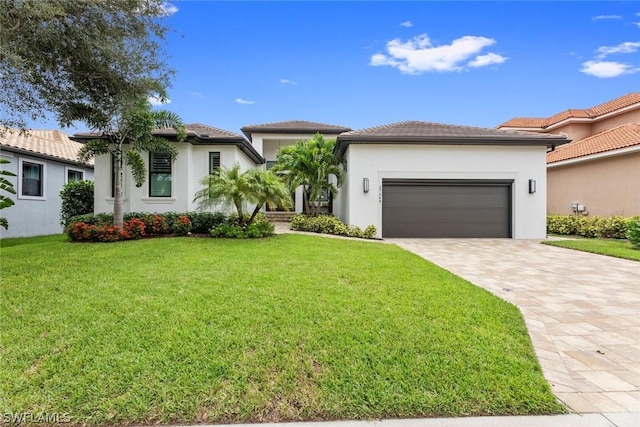 view of front of house featuring decorative driveway, an attached garage, stucco siding, and a front yard