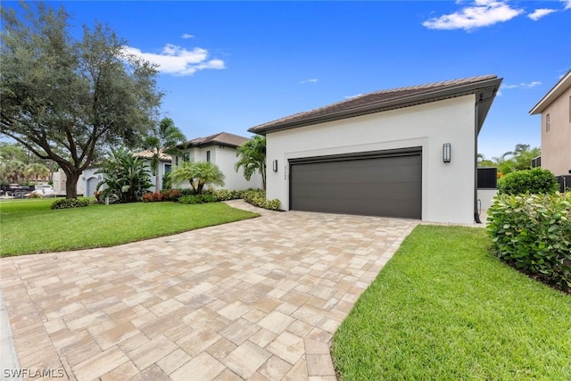 view of front of property with a garage, stucco siding, decorative driveway, and a front yard