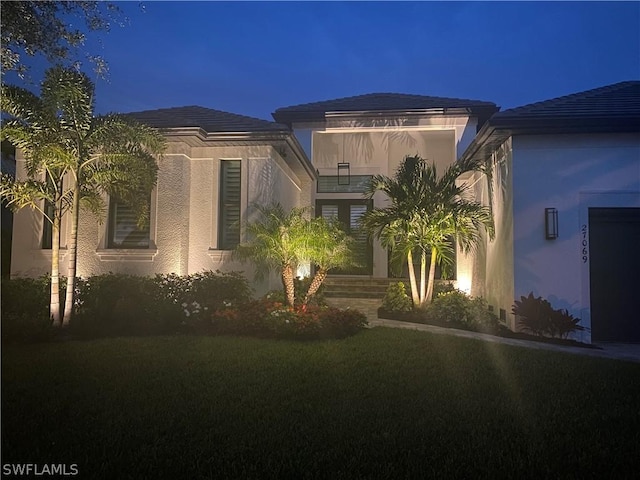 view of front of home with a lawn and stucco siding