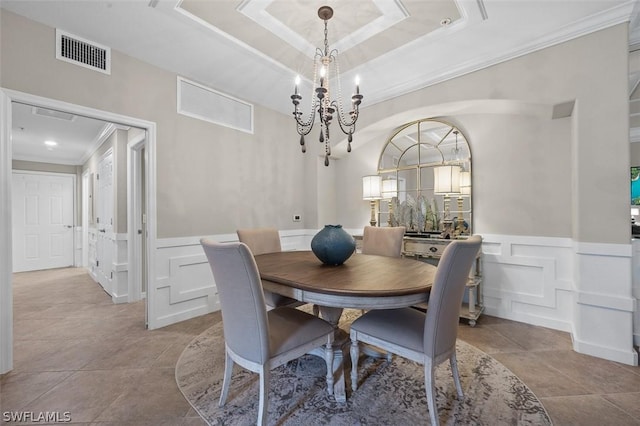 dining area featuring a raised ceiling, ornamental molding, and an inviting chandelier