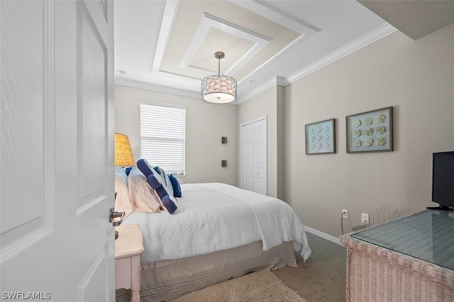 carpeted bedroom with a tray ceiling and ornamental molding