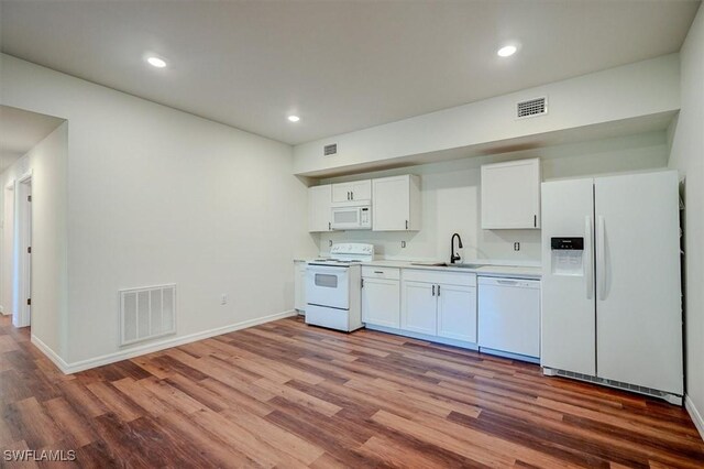 kitchen featuring wood finished floors, visible vents, a sink, and white appliances