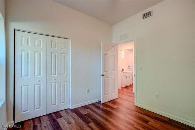 unfurnished bedroom featuring baseboards, wood finished floors, and visible vents