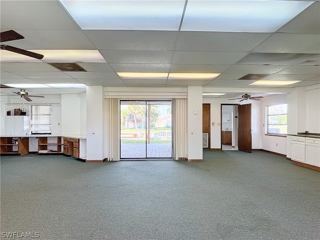 unfurnished living room featuring a paneled ceiling, carpet flooring, and plenty of natural light