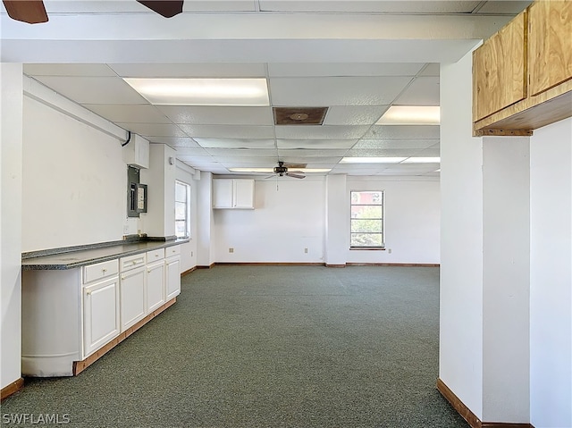 basement with a drop ceiling and dark colored carpet