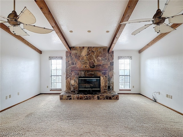 unfurnished living room featuring a stone fireplace, carpet floors, beamed ceiling, and a wealth of natural light