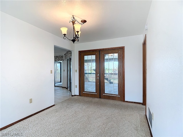 unfurnished room featuring french doors, light carpet, and a chandelier