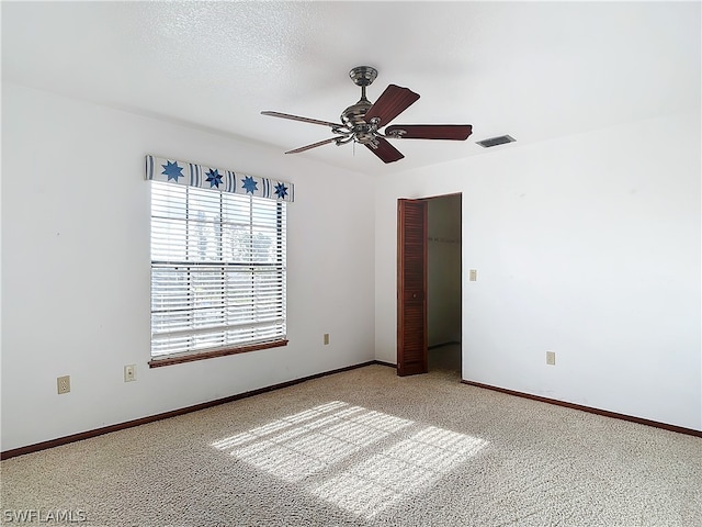 carpeted spare room with a textured ceiling and ceiling fan