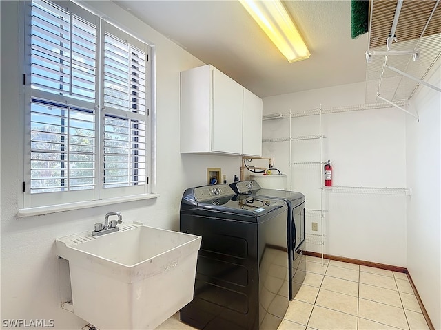 clothes washing area with sink, independent washer and dryer, light tile patterned floors, and cabinets