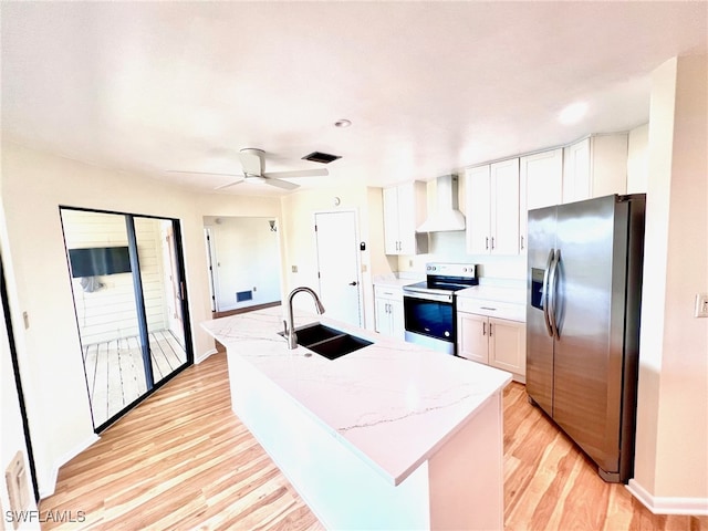 kitchen featuring wall chimney range hood, sink, an island with sink, white cabinetry, and stainless steel appliances