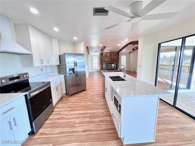 kitchen featuring a center island with sink, light hardwood / wood-style flooring, sink, wall chimney exhaust hood, and stainless steel appliances