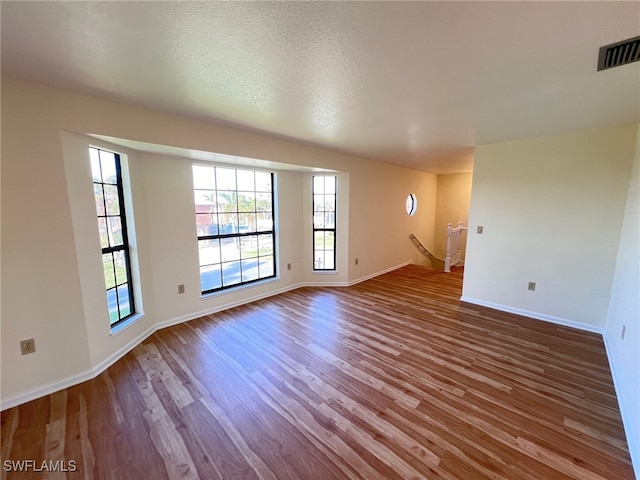 unfurnished room featuring hardwood / wood-style flooring and a textured ceiling