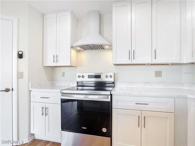 24313 Pirate Harbor Blvd, Punta Gorda, FL 33955 - kitchen with white cabinets, light wood-style floors, stainless steel range with electric stovetop, and wall chimney range hood