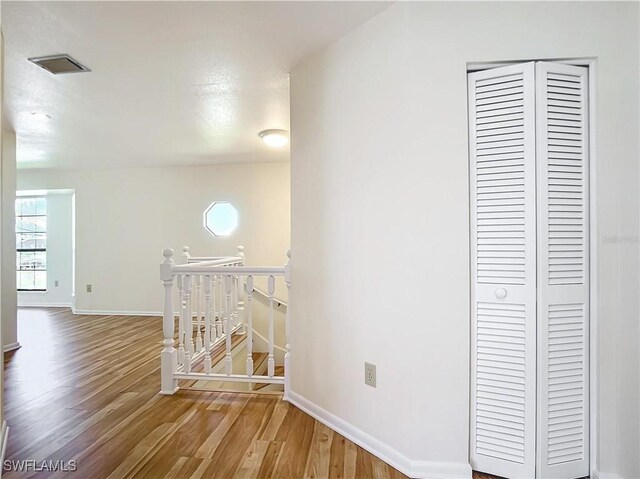 24313 Pirate Harbor Blvd, Punta Gorda, FL 33955 - hall with wood finished floors, visible vents, baseboards, and an upstairs landing