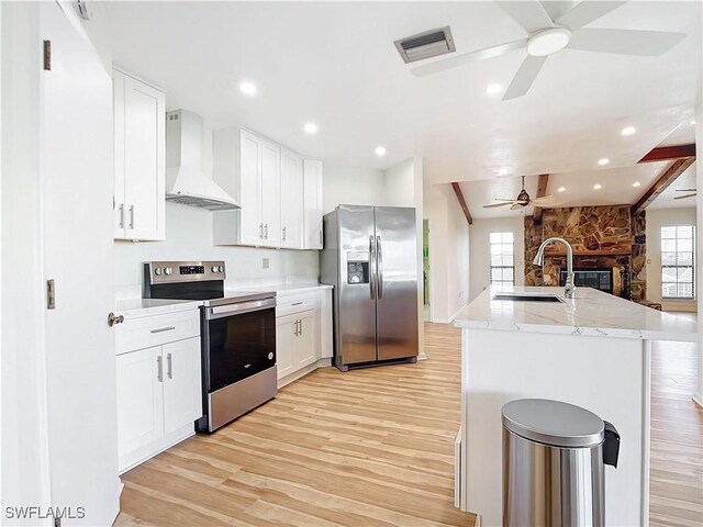 24313 Pirate Harbor Blvd, Punta Gorda, FL 33955 - kitchen with wall chimney exhaust hood, light wood finished floors, a sink, a ceiling fan, and appliances with stainless steel finishes