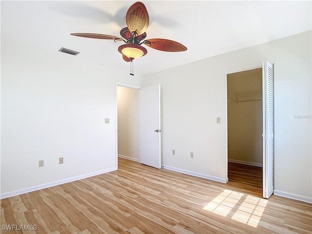 24313 Pirate Harbor Blvd, Punta Gorda, FL 33955 - unfurnished bedroom featuring a closet, a walk in closet, light wood finished floors, baseboards, and visible vents