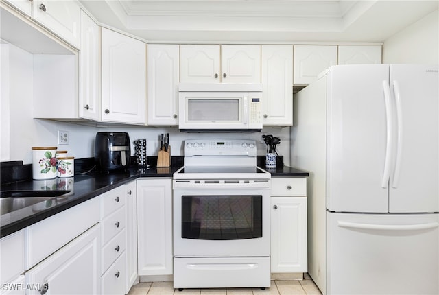 kitchen with dark countertops, white appliances, white cabinetry, and light tile patterned flooring