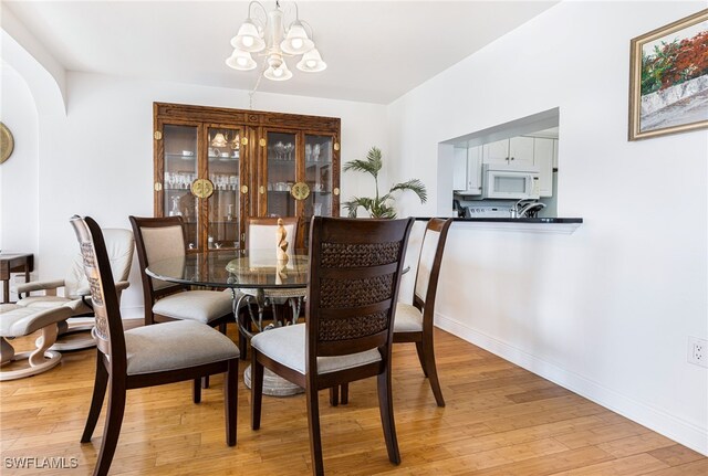 dining space with a notable chandelier and light hardwood / wood-style floors