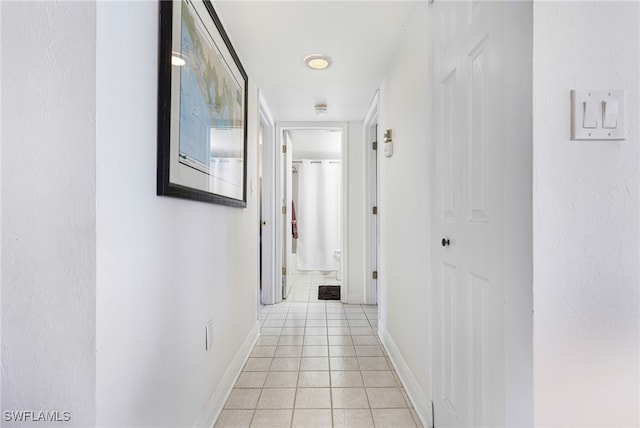 corridor featuring light tile patterned floors and baseboards