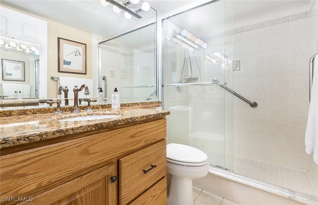 bathroom featuring a shower with shower door, vanity, toilet, and tile patterned flooring