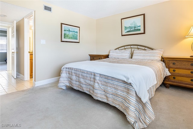 bedroom with baseboards, light tile patterned flooring, visible vents, and light colored carpet