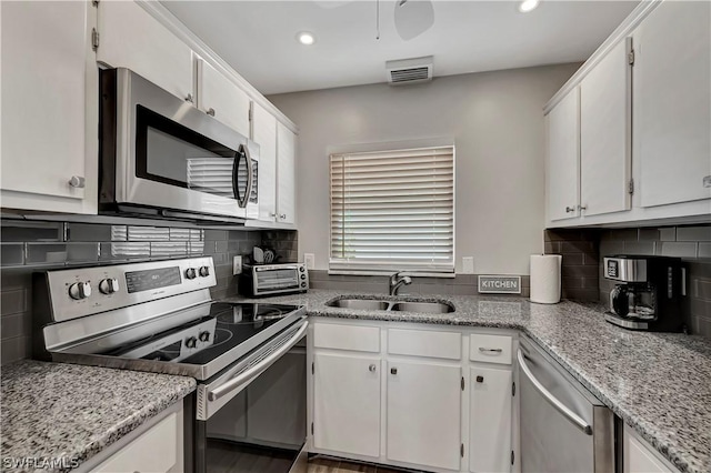 kitchen featuring sink, light stone countertops, tasteful backsplash, white cabinetry, and stainless steel appliances