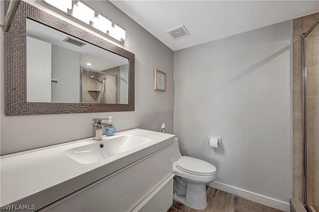 bathroom with hardwood / wood-style flooring, vanity, an enclosed shower, and toilet