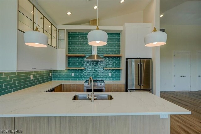 kitchen with light stone counters, wall chimney exhaust hood, stainless steel appliances, pendant lighting, and lofted ceiling