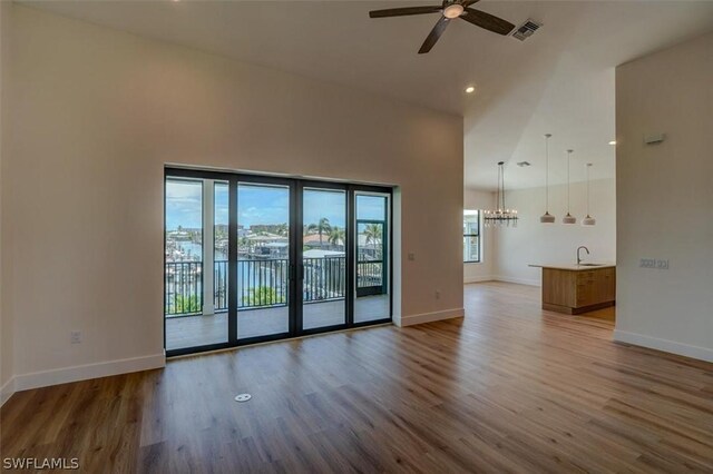 spare room featuring ceiling fan with notable chandelier, hardwood / wood-style flooring, a healthy amount of sunlight, and sink