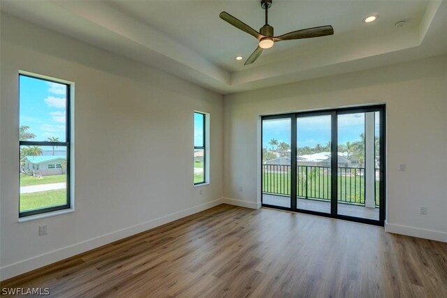 unfurnished room featuring ceiling fan, light hardwood / wood-style floors, and a raised ceiling