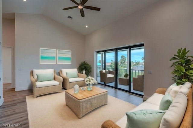 living room with ceiling fan, light wood-type flooring, and high vaulted ceiling