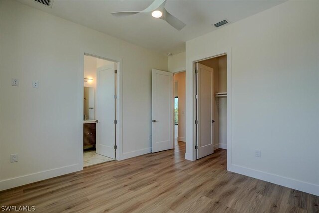 unfurnished bedroom with ceiling fan, light hardwood / wood-style flooring, ensuite bathroom, a walk in closet, and a closet