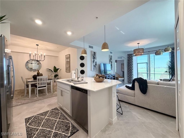 kitchen with a kitchen island with sink, stainless steel appliances, decorative light fixtures, sink, and white cabinets