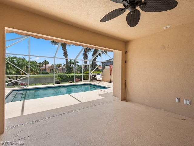 view of pool with ceiling fan, a water view, a patio, and glass enclosure