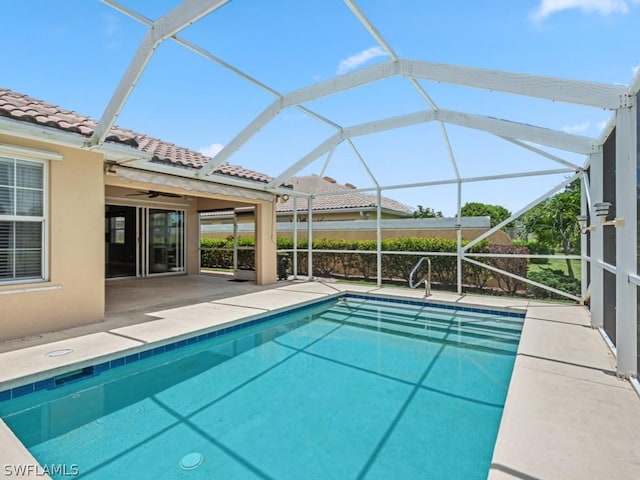 view of pool featuring glass enclosure, ceiling fan, and a patio