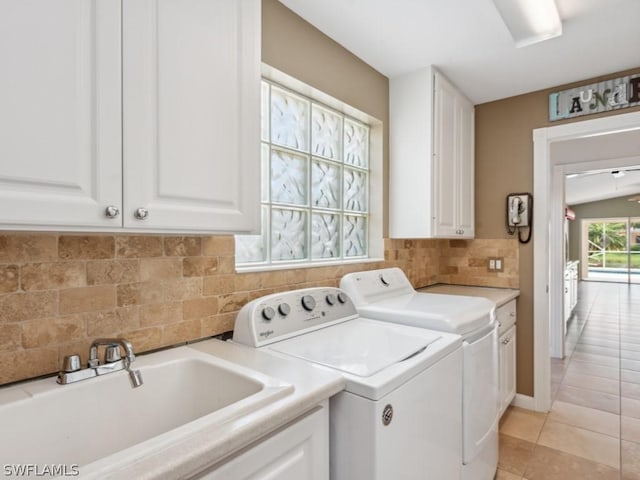 laundry room featuring cabinets, light tile patterned floors, washer and dryer, and sink